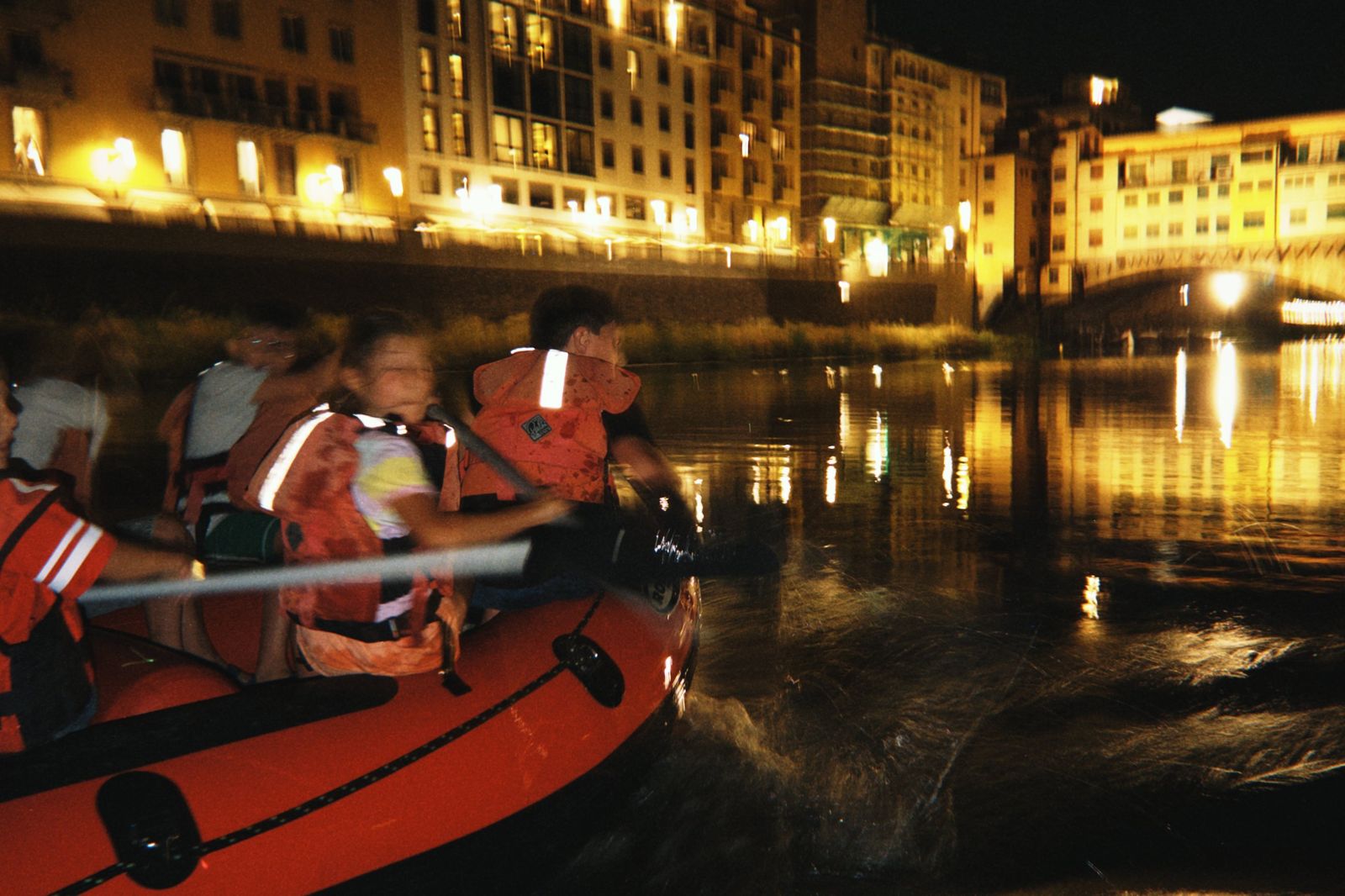 Gommone sull'Arno di notte con i lungarni illuminati la sera di San Giovanni a Firenze