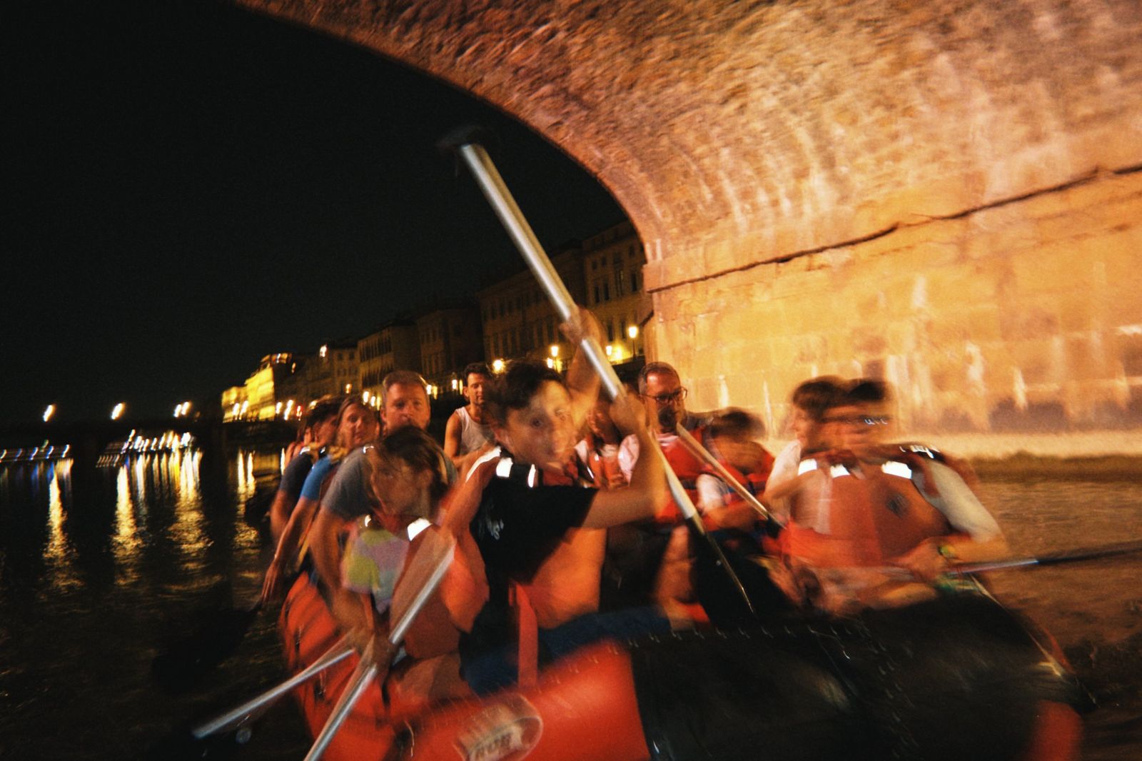 Gruppo in rafting sotto un ponte di Firenze la notte di San Giovanni